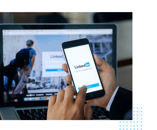 person looking at LinkedIn site on phone & computer